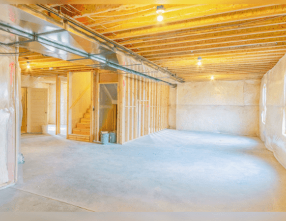 Residential basement under construction with visible vapor barrier installation for moisture protection.