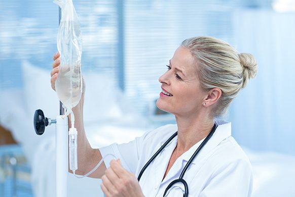 Smiling healthcare professional adjusting IV fluid bag in clinical setting
