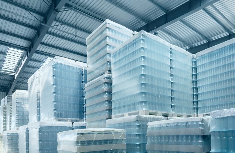 Pallets stacked with bottled products secured using transparent stretch hood film