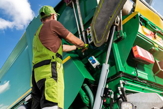 Worker in safety gear operating green industrial machinery outdoors