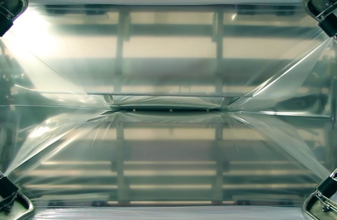Stretch hood film being applied to a pallet load through automated machinery