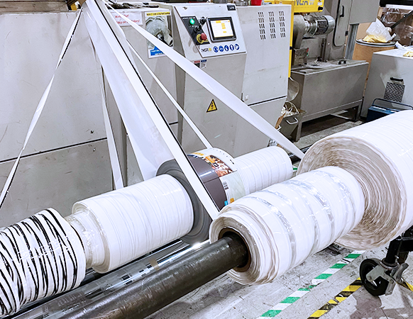 Industrial recycling equipment processing plastic film scrap into new rolls for post-industrial recycled material production.