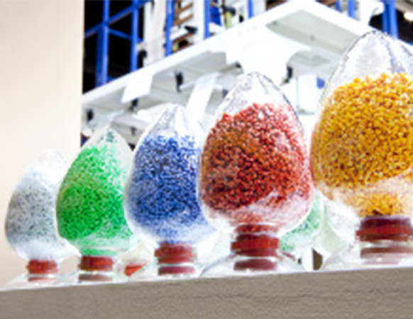 Assorted plastic resin pellets in clear containers representing raw materials for film and packaging production.