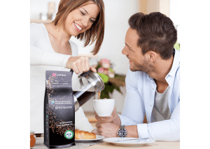 Smiling couple enjoying coffee at home with a Layfield-branded flexible coffee pouch displayed prominently on the table.