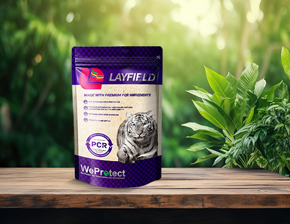 Layfield flexible stand-up pouch featuring PCR content labeling, placed on a wooden surface with a green natural background.